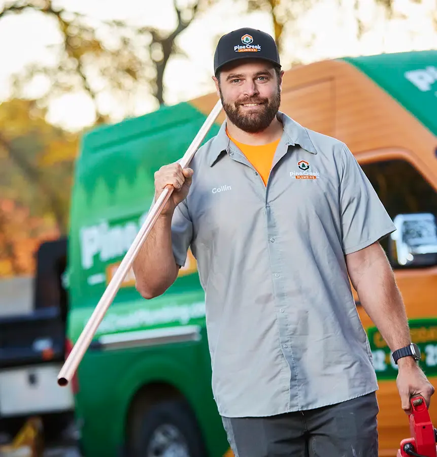 Friendly Pine Creek Plumber holding pipe with truck in background