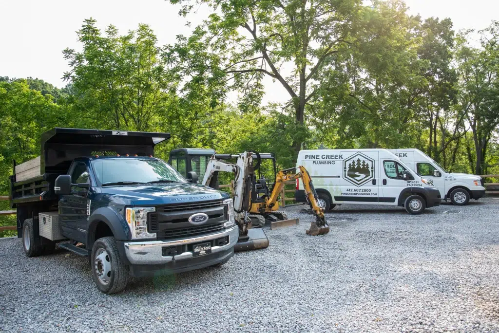 Pine Creek Plumbing trucks and excavator in Wexford.