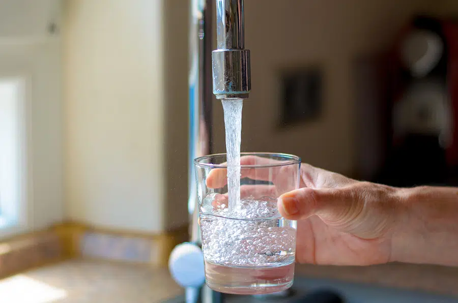 homeowner filling glass of filtered drinking water from kitchen sink